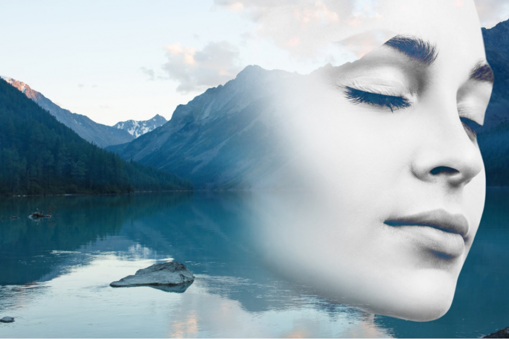 A mountain with water and a reflection of a woman over the water